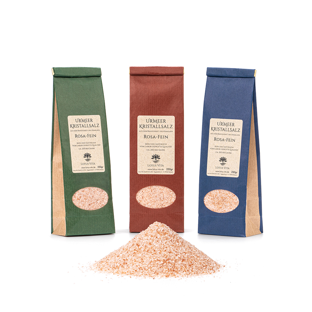 Drei 250g-Beutel mit fein gemahlenem, rosa Kristallsalz in grüner, roter und blauer Verpackung, davor eine kleine Menge des losen Salzes.