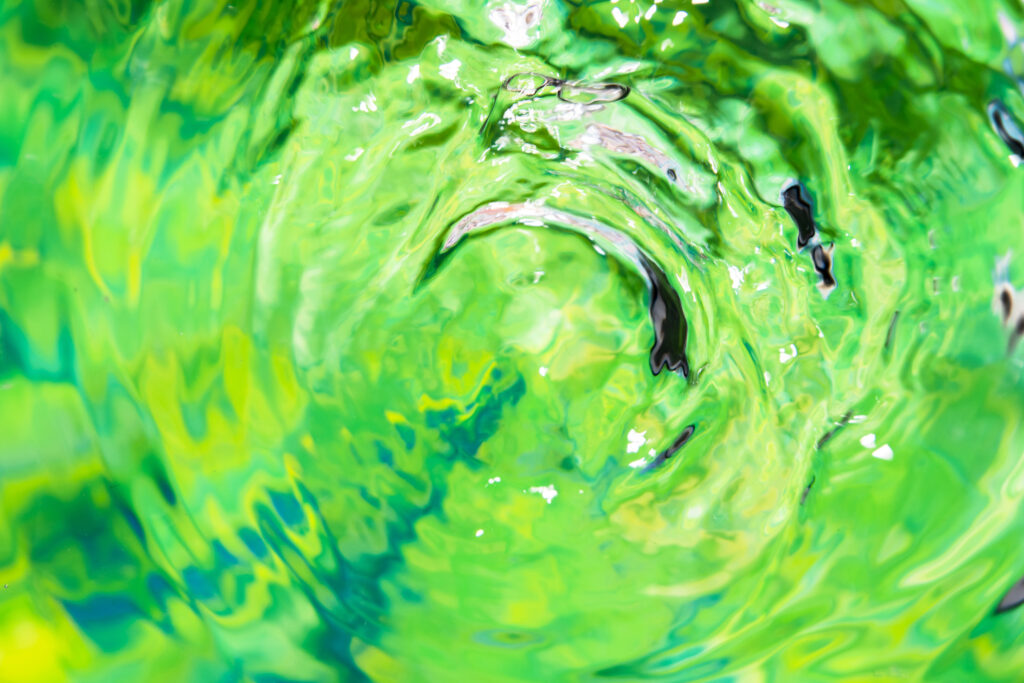 Nahaufnahme von reinem, bewegtem Wasser, das in vitalisierenden Grün- und Gelbtönen leuchtet.