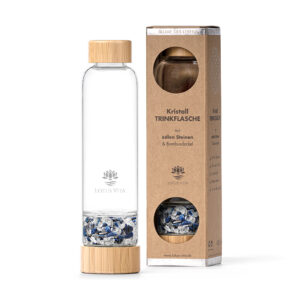 Eine Glas-Trinkflasche von Lotus Vita mit Bambusdeckel und einem separaten Fach gefüllt mit blauen und weißen Kristallen, neben der Produktverpackung aus Karton.