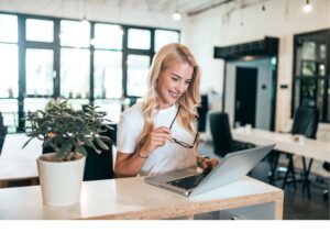 Eine Frau sitzt lächelnd vor ihrem Laptop und nimmt am Lotus Vita Empfehlungsprogramm teil.