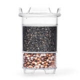 Eine transparente Wasserfilter-Kartusche, die im oberen Bereich mit Aktivkohle und im unteren Bereich mit Mineralkugeln gefüllt ist.