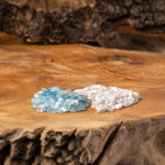 Eine Edelsteinmischung aus himmelblauem Aquamarin und reinweißem Milchopal liegt auf einer rustikalen Holzoberfläche.